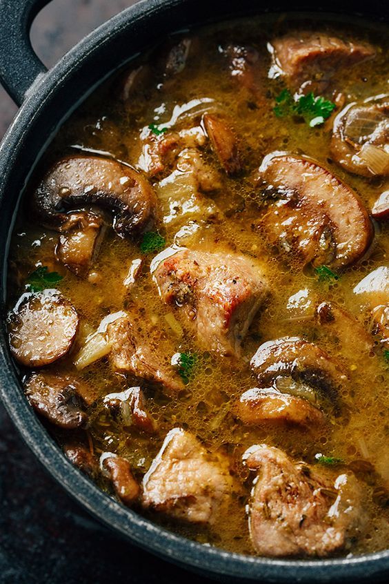 a pan filled with meat and mushrooms on top of a table