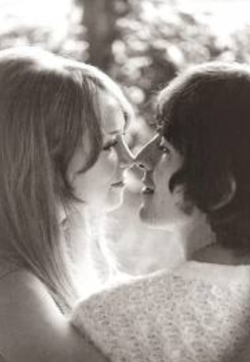 black and white photograph of two women facing each other with trees in the back ground