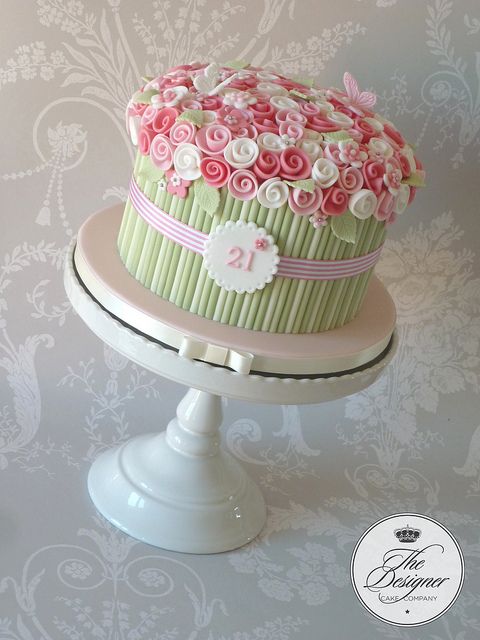 a pink and green cake sitting on top of a white pedestal