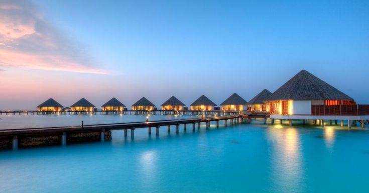 the water is blue and clear with some huts on it's sides at night