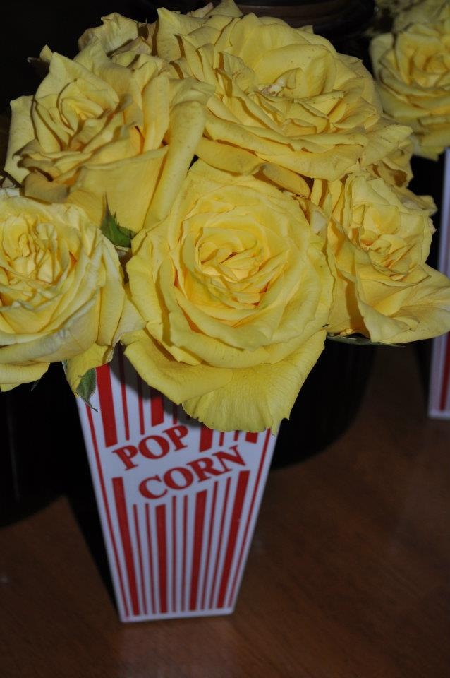 yellow roses are in a popcorn box on the table