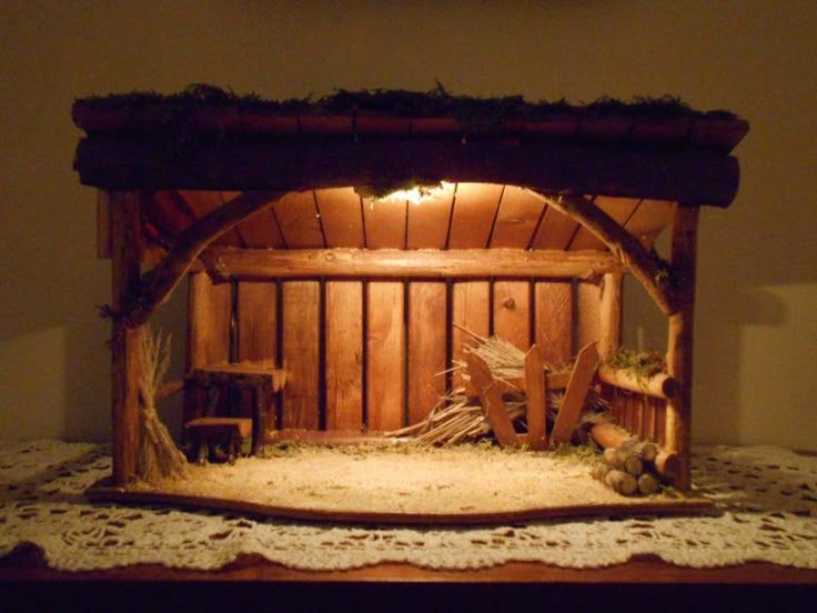 a nativity scene is displayed on a table with white doily and crib