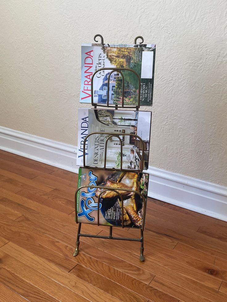 a magazine rack with magazines on it in front of a wall and hardwood flooring