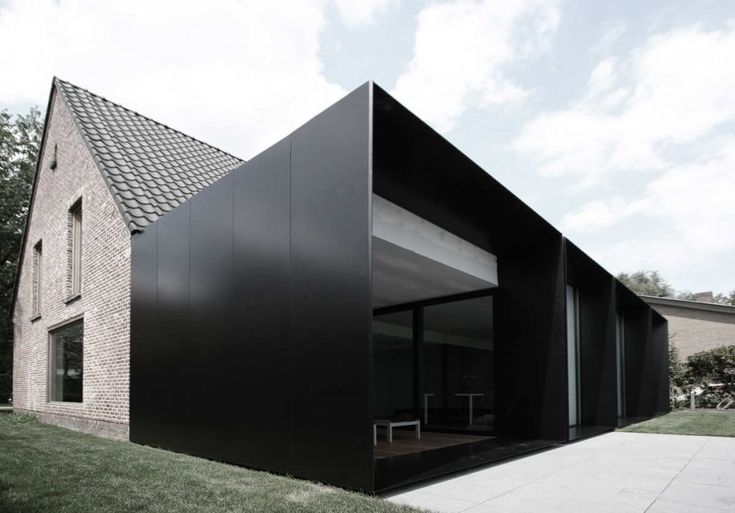 a black building sitting on top of a lush green field