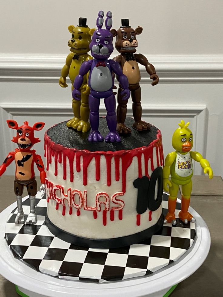 a cake decorated with five cartoon characters on top of a black and white checkered table