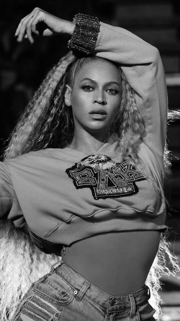 a black and white photo of a woman with her arms behind her head wearing jeans