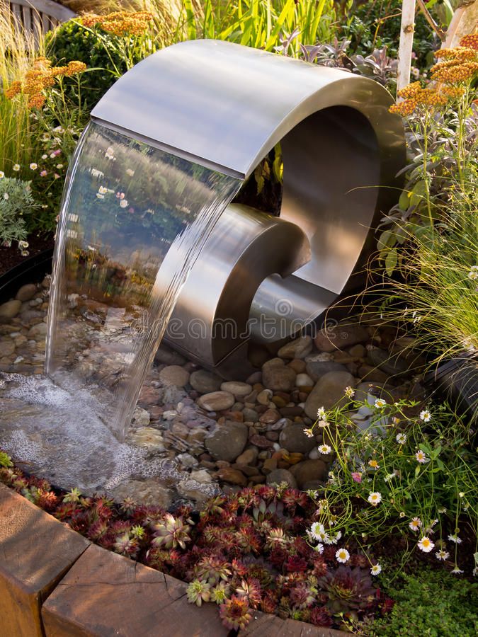 a water feature in a garden with rocks and plants around it stock images, royalty photos