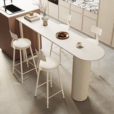 a kitchen table with three stools next to it and an island in the middle