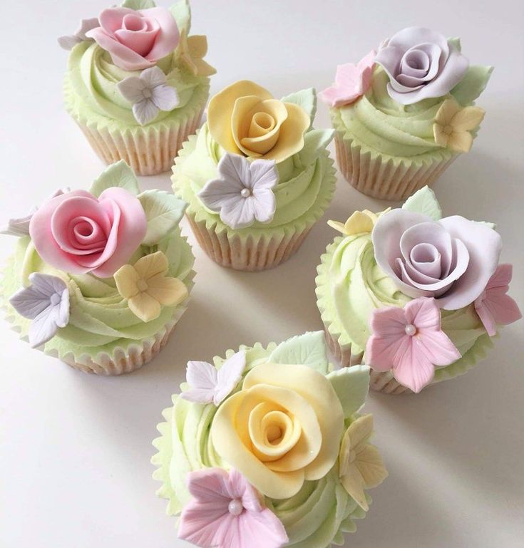 cupcakes decorated with flowers and leaves are arranged in a circle on a table