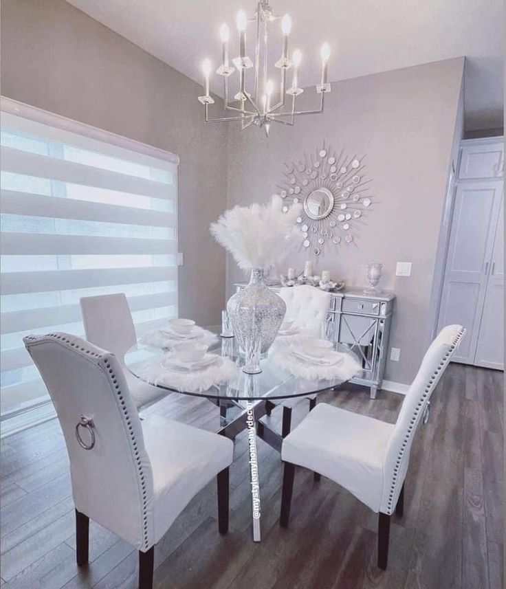 a dining room table with white chairs and chandelier