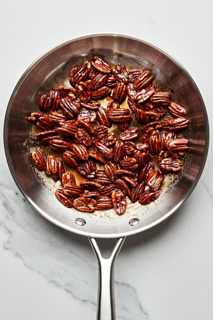 pecans in a frying pan on a marble counter