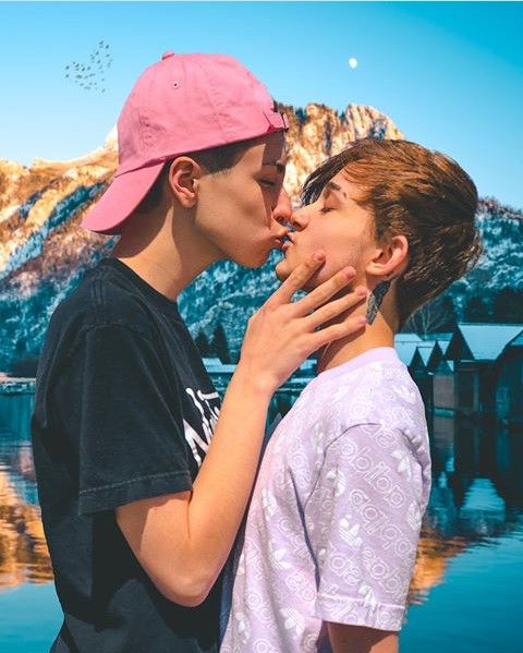 two boys kissing each other in front of mountains