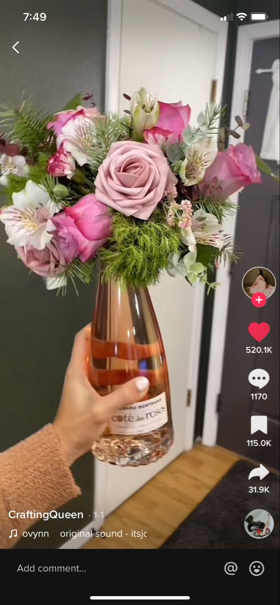 someone is holding a vase with flowers in it on their cell phone and taking a photo