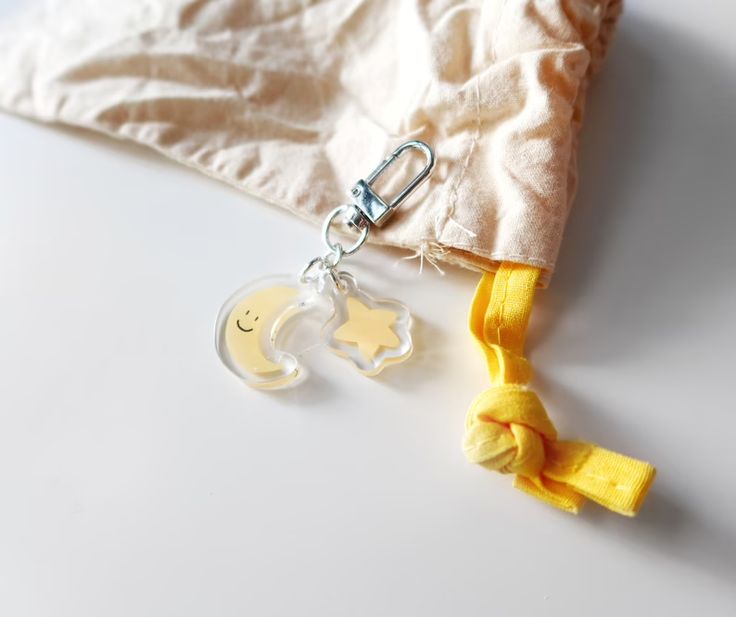 a keychain with a pacifier attached to it next to a cloth bag