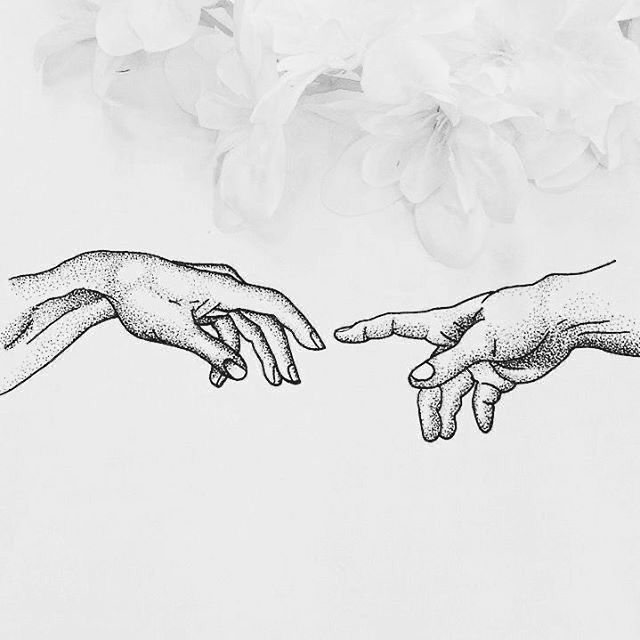 two hands touching each other with flowers in the background