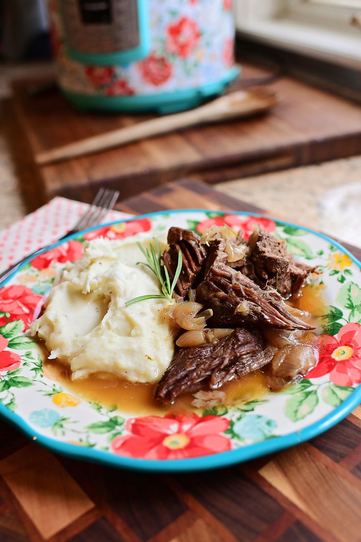 a plate with meat, mashed potatoes and gravy sits on a table