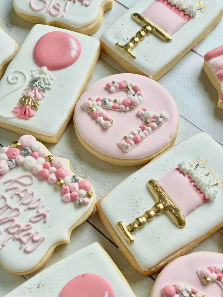 decorated cookies with pink and white frosting are arranged on a table together in the shape of letters