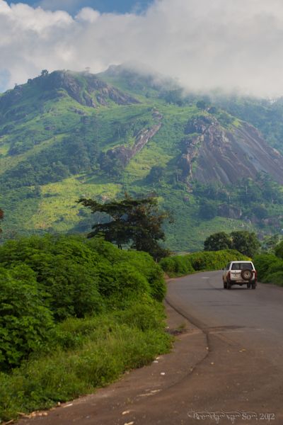 a car driving down the road in front of a mountain