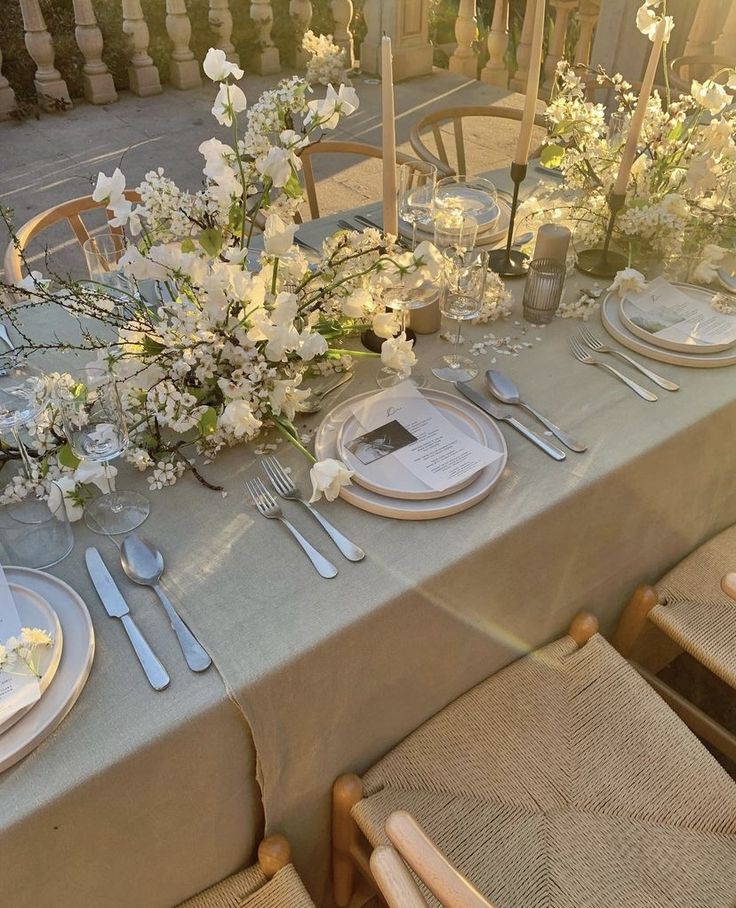 the table is set with silverware and flowers