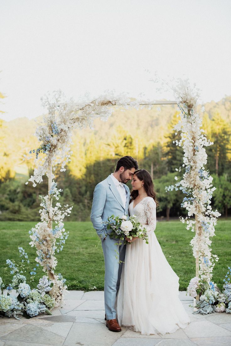 a bride and groom standing under an arch decorated with flowers