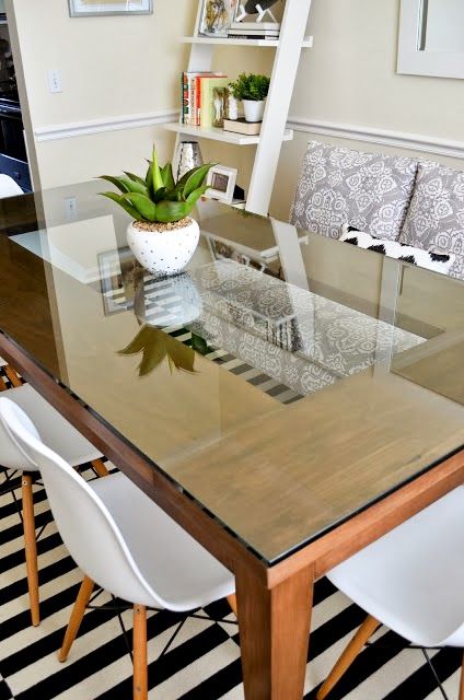 a dining room table with white chairs and a potted plant on top of it