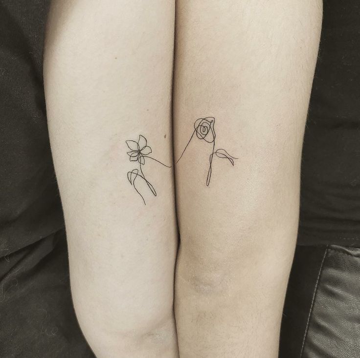 two people with matching tattoos on their legs, one has a flower and the other has a bird