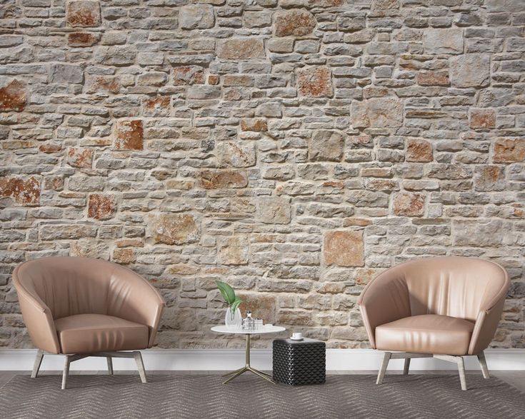 two chairs sitting next to each other in front of a stone wall