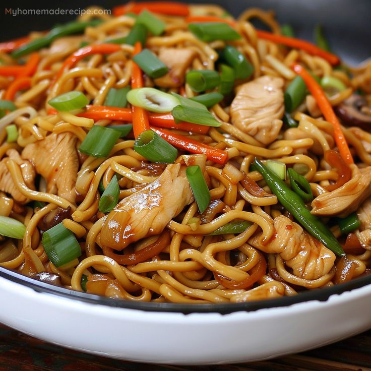 a bowl full of noodles with chicken and vegetables