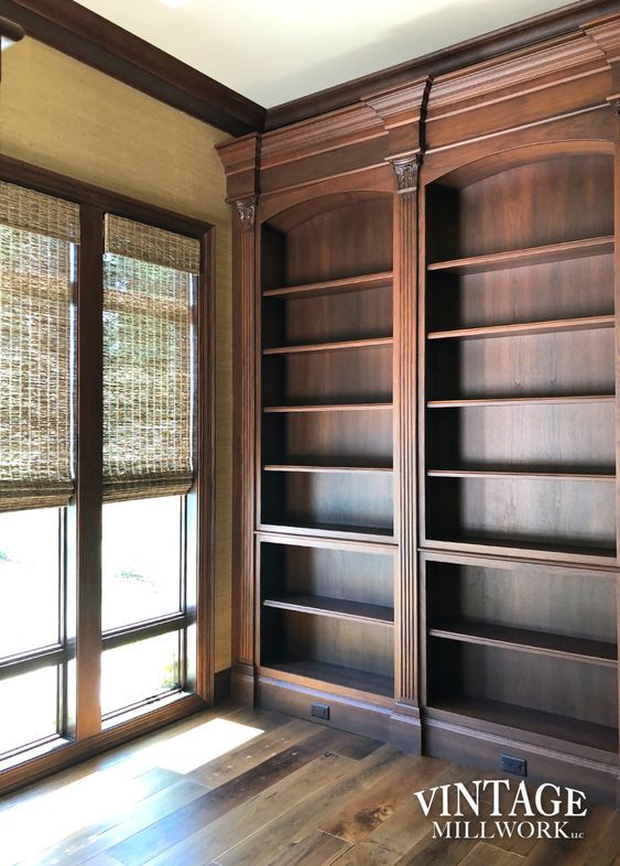 an empty room with wooden bookshelves and windows