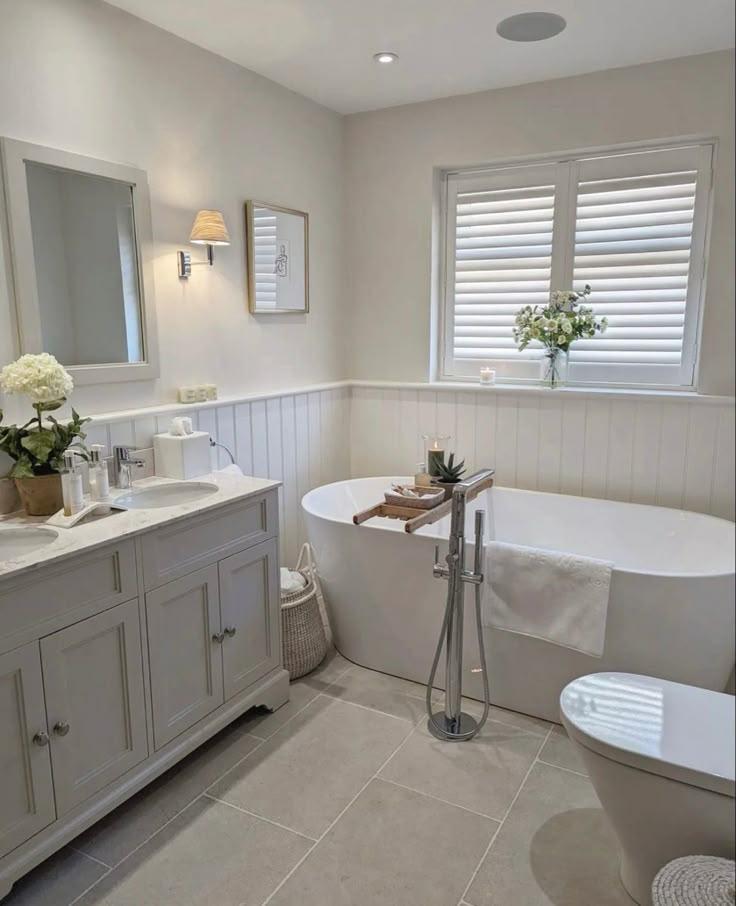 a white bathroom with a tub, sink and window in it's center area