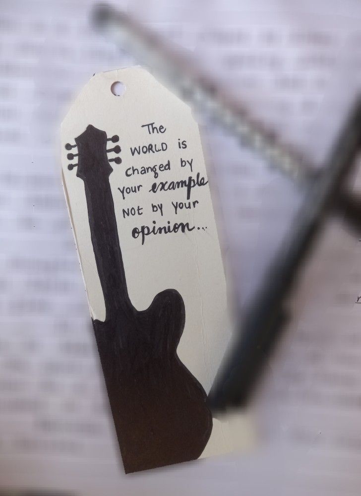 a bookmark with an image of a guitar and the words, the world is changed by your example not by your opinion