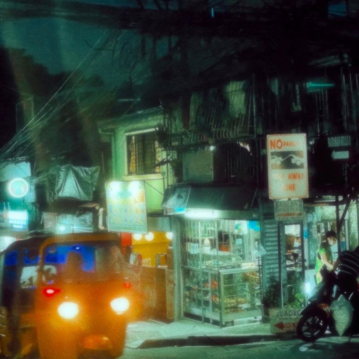 a car driving down a street next to a tall building with neon lights on it