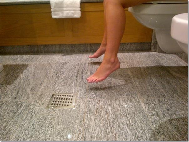 a person standing on the edge of a toilet in a bathroom