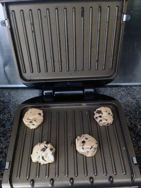 four chocolate chip cookies are being cooked on the grill