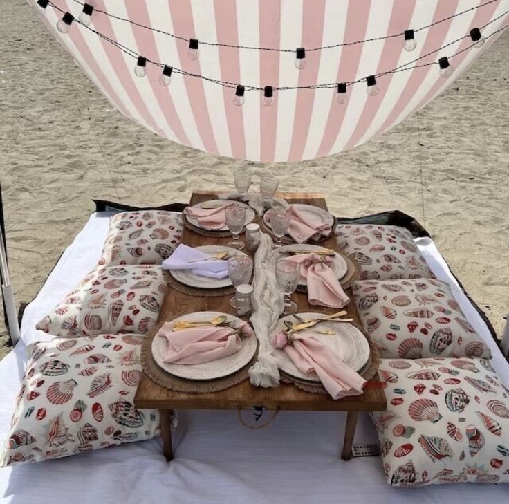 a picnic table set up on the beach with plates and napkins laid out in front of it