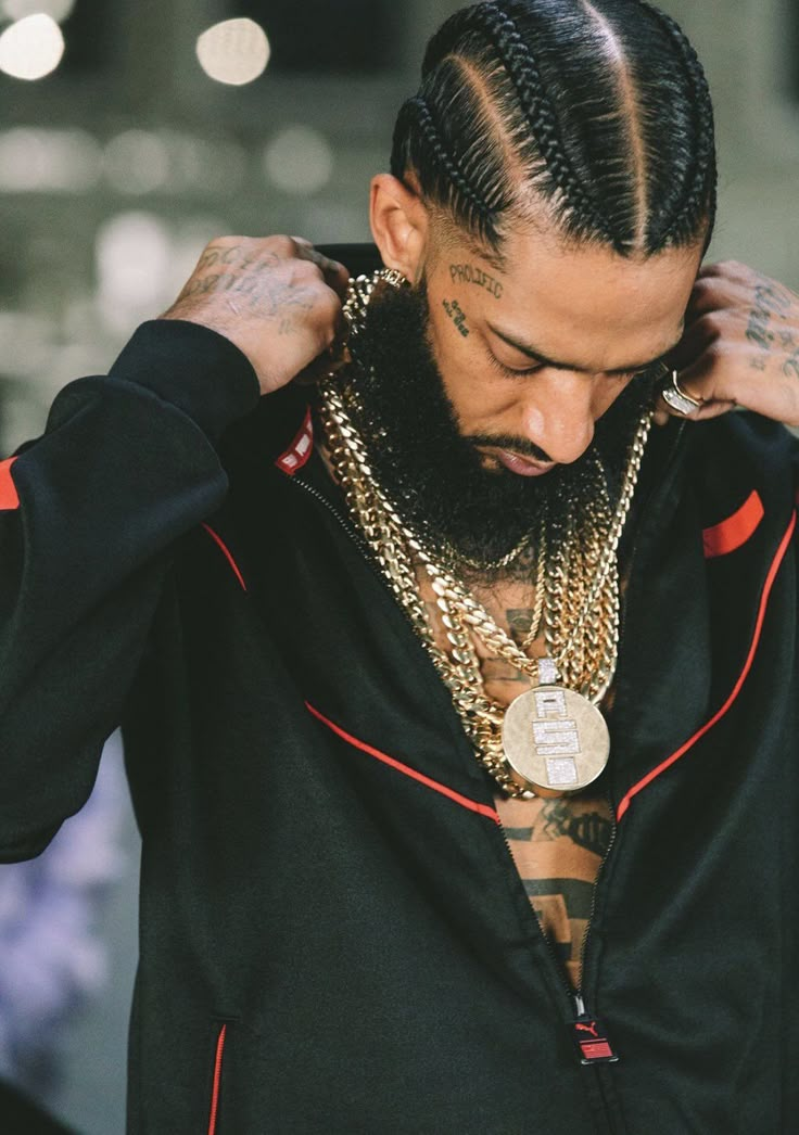 a man with dreadlocks wearing a black jacket and gold chain around his neck