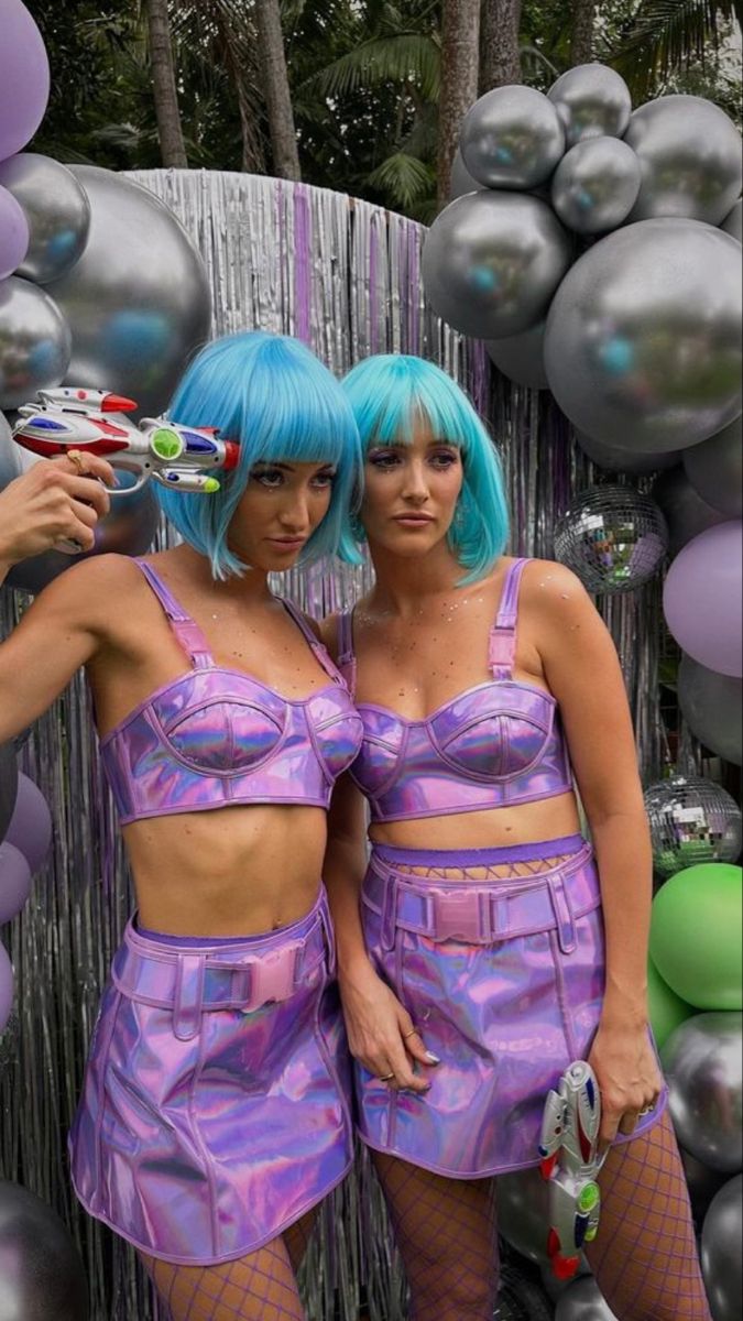 two women with blue hair standing next to each other in front of balloons and streamers