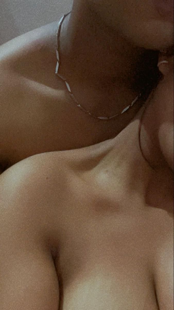 a close up of a woman with no shirt on laying down and wearing a necklace