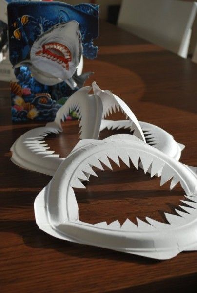 two paper plates with shark teeth on them sitting on a table next to a bag of candy