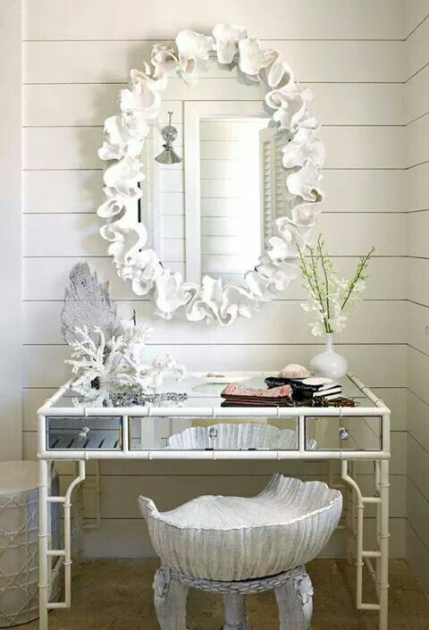 a white table with a mirror and vase on it