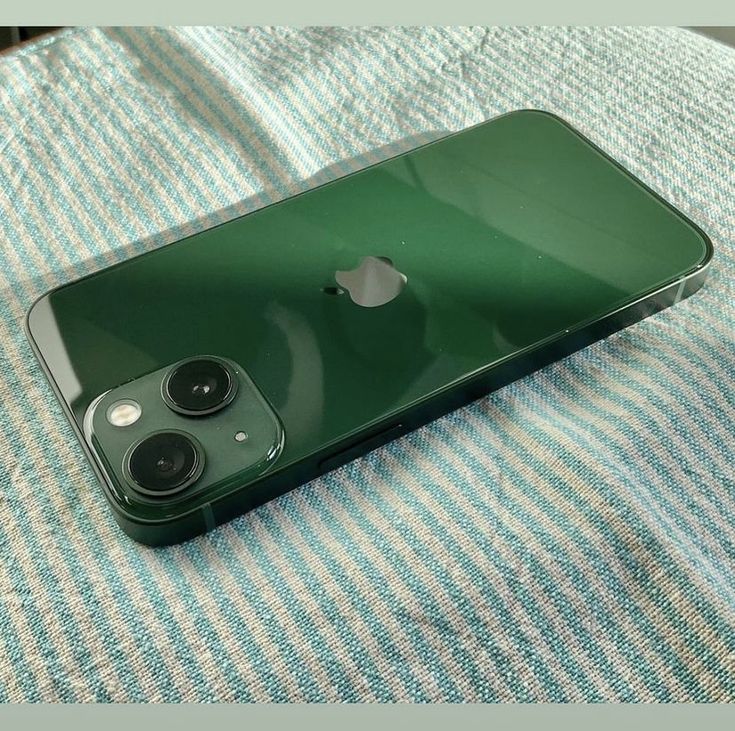 an iphone is sitting on top of a blue and white striped cloth with two cameras attached to it