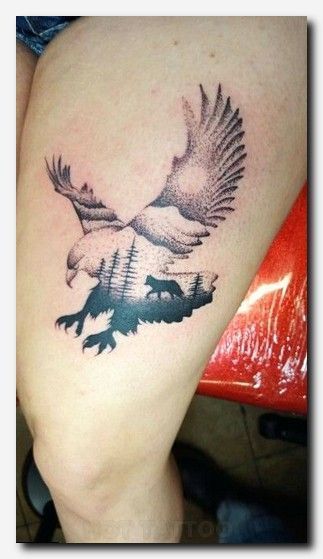 an eagle and bear tattoo on the thigh, with trees in the backgrund