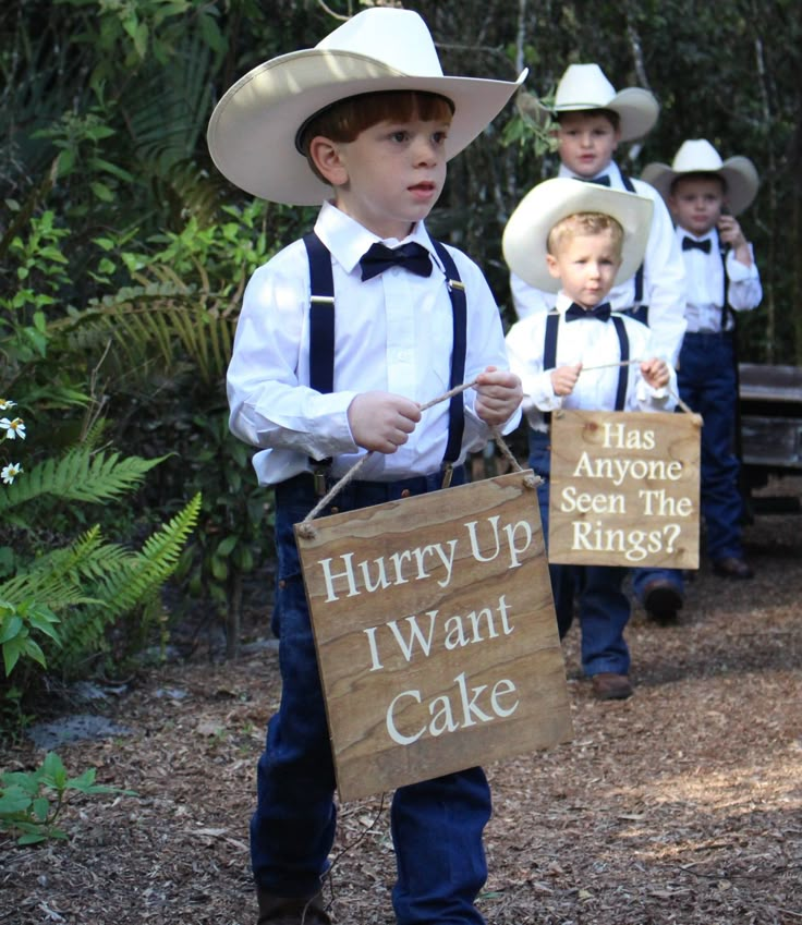 a group of young boys wearing cowboy hats and holding signs that read hurry up i want cake