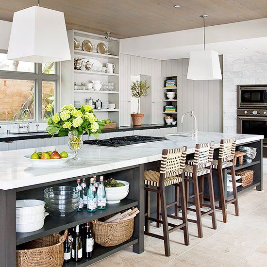 a large kitchen with lots of counter space and stools around the center island in front of an oven