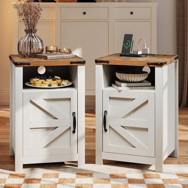 two white side tables with open doors and plates on them