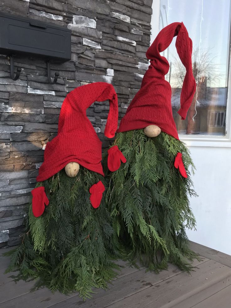 two gnome hats sitting on top of evergreen branches