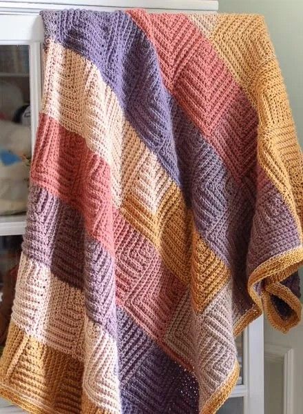 a multicolored crocheted blanket sitting on top of a window sill