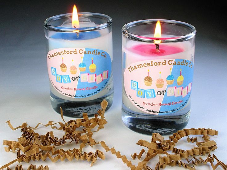 two candles sitting next to each other on top of a white table with brown paper streamers