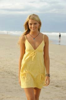 a woman in a yellow dress is walking on the beach