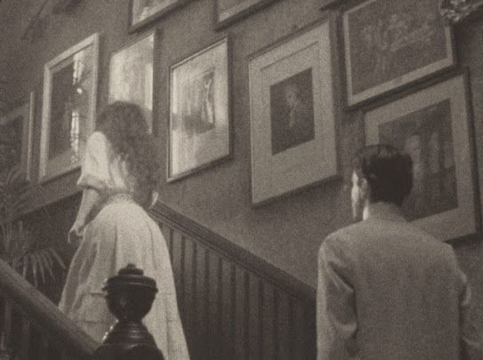 two people are walking up the stairs in front of pictures hanging on the wall behind them